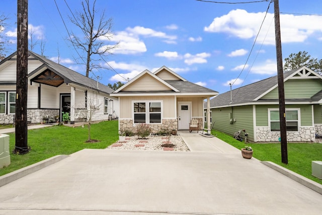 craftsman-style home with board and batten siding, a front yard, and stone siding