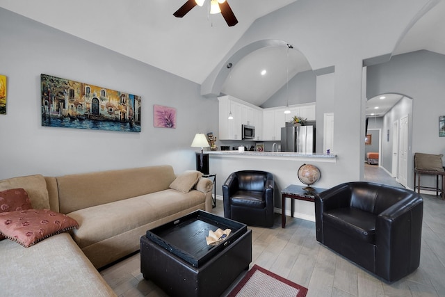 living room featuring arched walkways, baseboards, light wood-style flooring, ceiling fan, and high vaulted ceiling