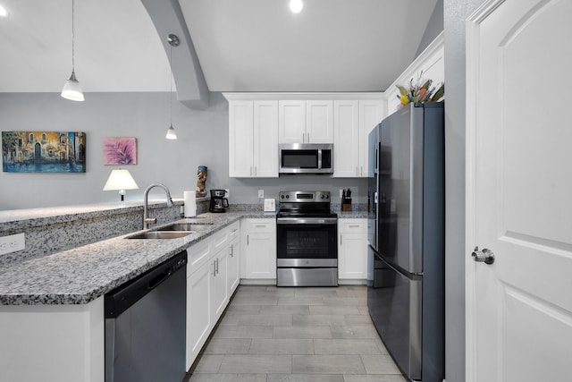 kitchen with appliances with stainless steel finishes, white cabinets, a sink, light stone countertops, and a peninsula