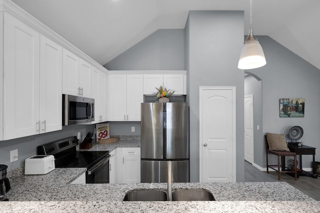 kitchen featuring arched walkways, white cabinets, vaulted ceiling, appliances with stainless steel finishes, and light stone countertops