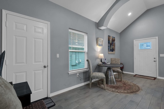 entryway with arched walkways, lofted ceiling, baseboards, and wood finished floors