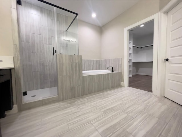 bathroom featuring a spacious closet, vanity, a shower stall, and a bath