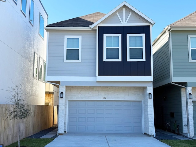 view of front of house with stone siding, fence, board and batten siding, and concrete driveway