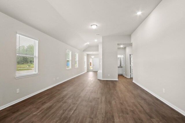 unfurnished living room with visible vents, dark wood-style flooring, baseboards, and lofted ceiling