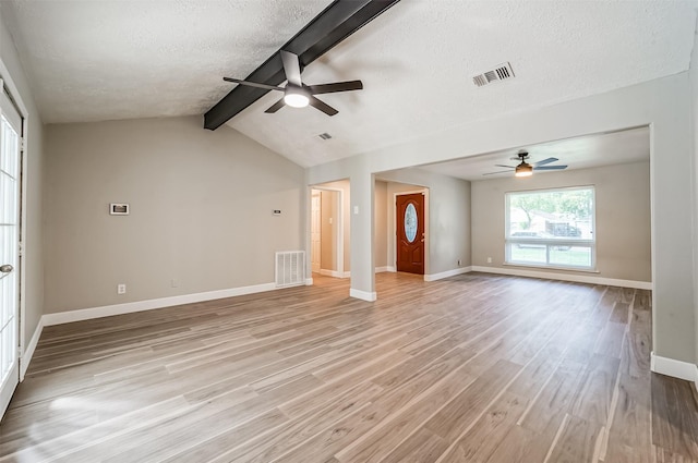 unfurnished living room featuring baseboards, light wood-style flooring, visible vents, and a textured ceiling