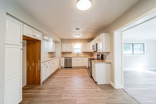 kitchen with visible vents, appliances with stainless steel finishes, a sink, and light wood-style flooring