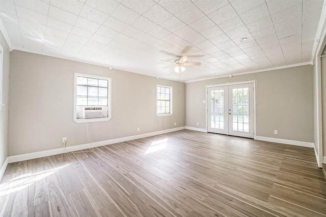 empty room with french doors, ornamental molding, wood finished floors, cooling unit, and baseboards