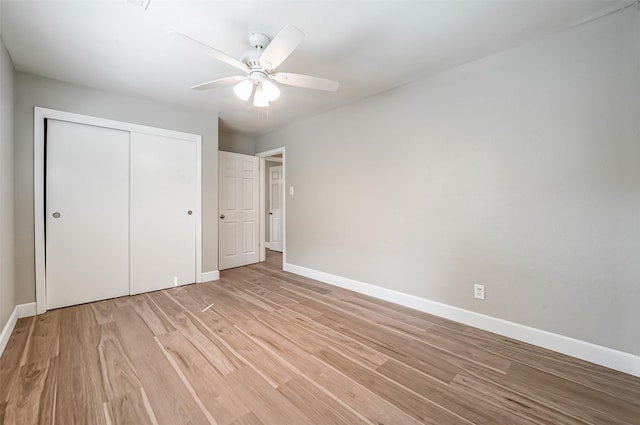 unfurnished bedroom featuring light wood-type flooring, a ceiling fan, baseboards, and a closet