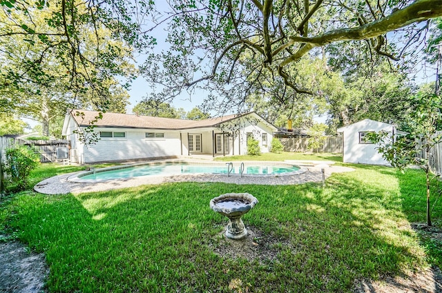 back of property featuring french doors, a fenced in pool, a fenced backyard, a yard, and an outdoor structure