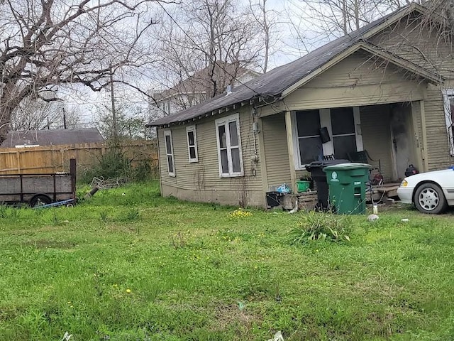 view of side of home with a lawn and fence