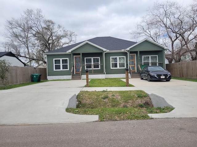 view of front of property featuring driveway, roof with shingles, and fence