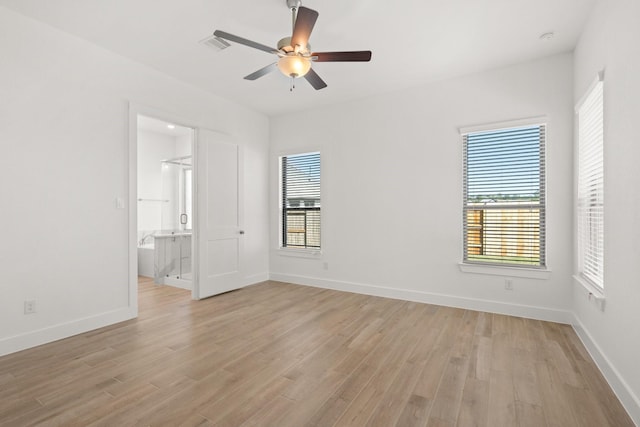 empty room with light wood finished floors, a wealth of natural light, and baseboards