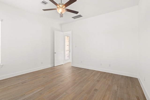 spare room with baseboards, ceiling fan, visible vents, and light wood-style floors