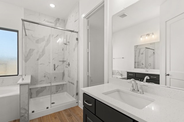 bathroom with a bath, wood finished floors, a marble finish shower, and visible vents