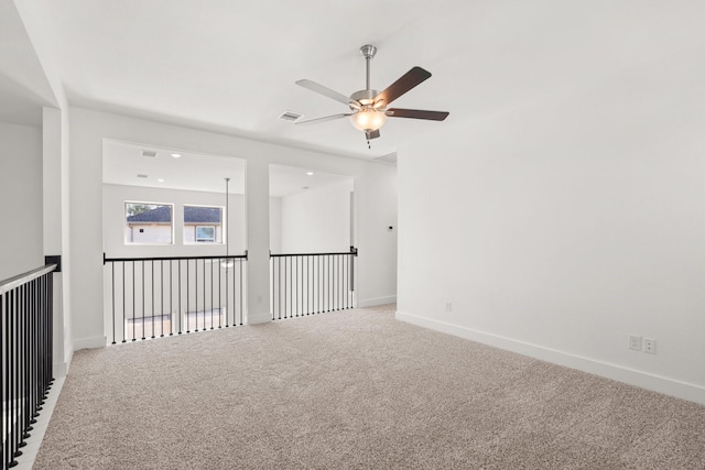 empty room featuring a ceiling fan, carpet, visible vents, and baseboards