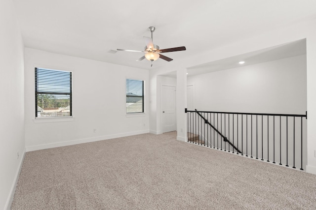 carpeted empty room featuring baseboards and a ceiling fan