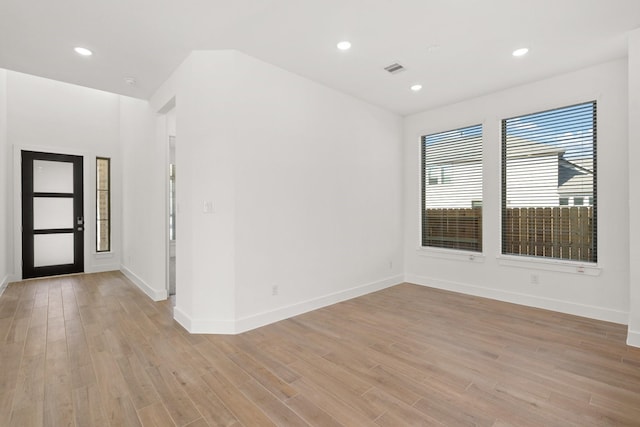 empty room featuring light wood-style floors, baseboards, visible vents, and recessed lighting