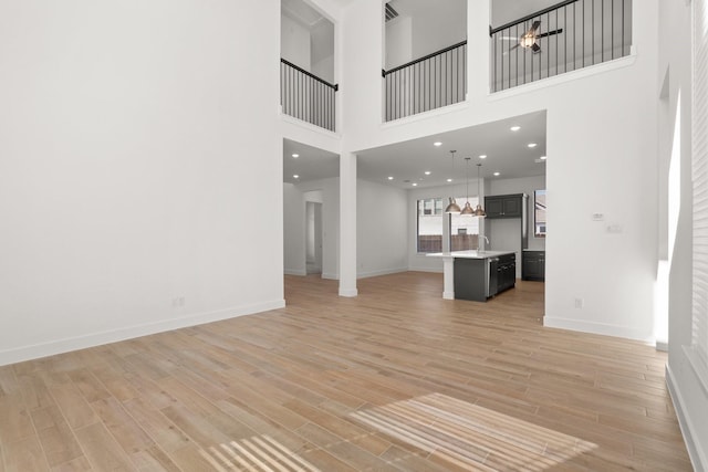 unfurnished living room featuring recessed lighting, baseboards, and light wood finished floors