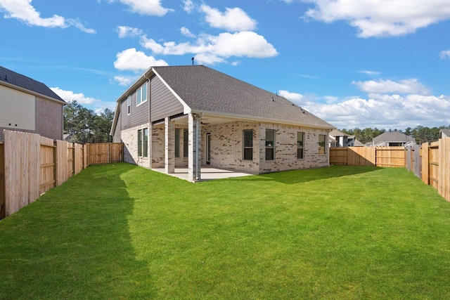 back of property featuring a patio, a fenced backyard, roof with shingles, a yard, and brick siding