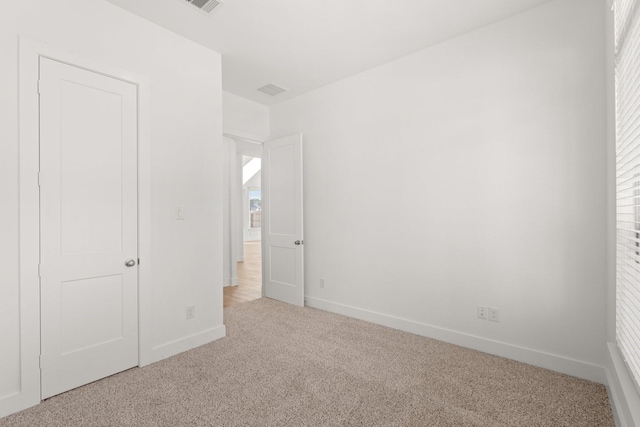 unfurnished bedroom featuring carpet, multiple windows, and baseboards