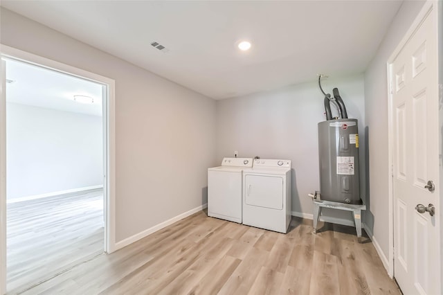 laundry room with washing machine and clothes dryer, water heater, light wood-type flooring, laundry area, and baseboards