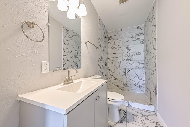 bathroom with a textured wall, toilet, marble finish floor, vanity, and a shower stall