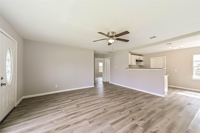 unfurnished living room featuring light wood-style flooring, plenty of natural light, visible vents, and baseboards