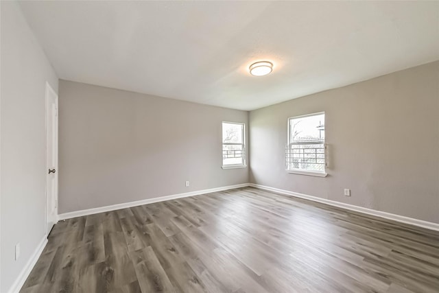 unfurnished room with dark wood-style flooring and baseboards