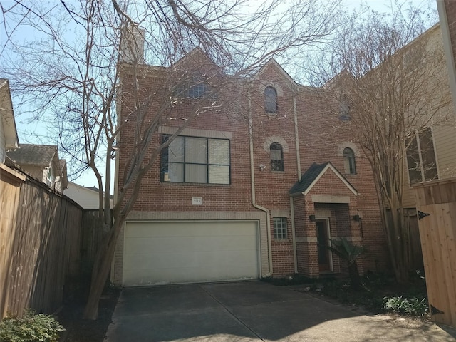 tudor-style house with brick siding, fence, driveway, and an attached garage