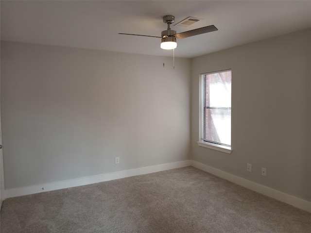 unfurnished room with carpet floors, visible vents, baseboards, and a ceiling fan