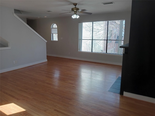 unfurnished living room featuring ceiling fan, wood finished floors, visible vents, and baseboards