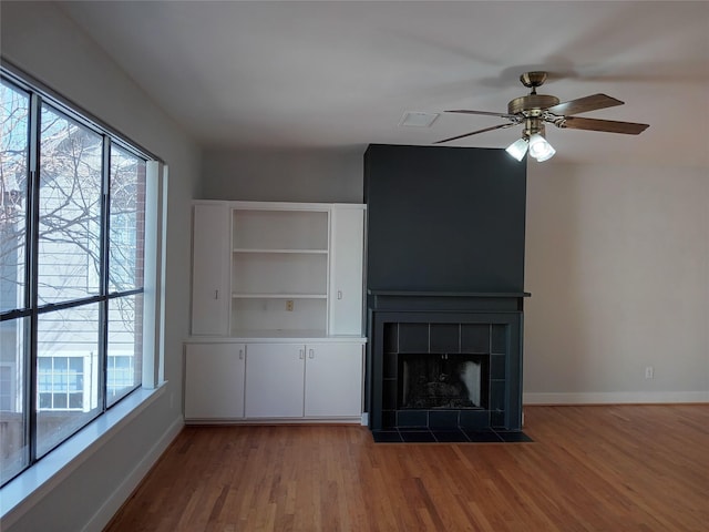 unfurnished living room featuring visible vents, a fireplace, baseboards, and wood finished floors