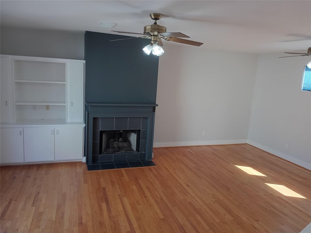 unfurnished living room featuring light wood-style flooring, a fireplace, baseboards, and a ceiling fan