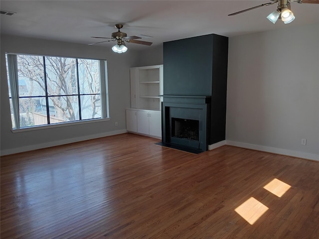 unfurnished living room with a ceiling fan, a fireplace, baseboards, and wood finished floors