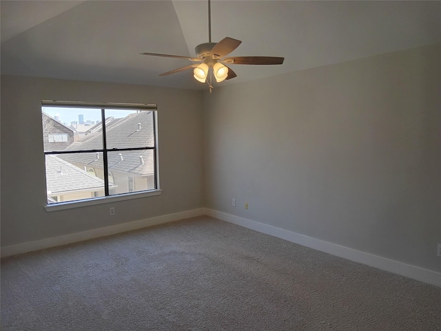 empty room with vaulted ceiling, light colored carpet, ceiling fan, and baseboards