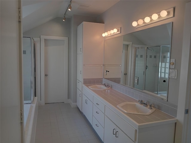 bathroom with vaulted ceiling, tasteful backsplash, a sink, and a shower with door