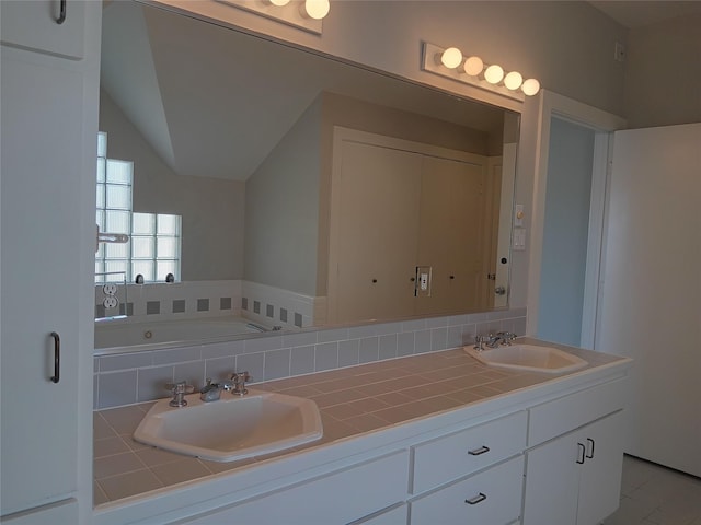 bathroom with a bathtub, lofted ceiling, a sink, and double vanity