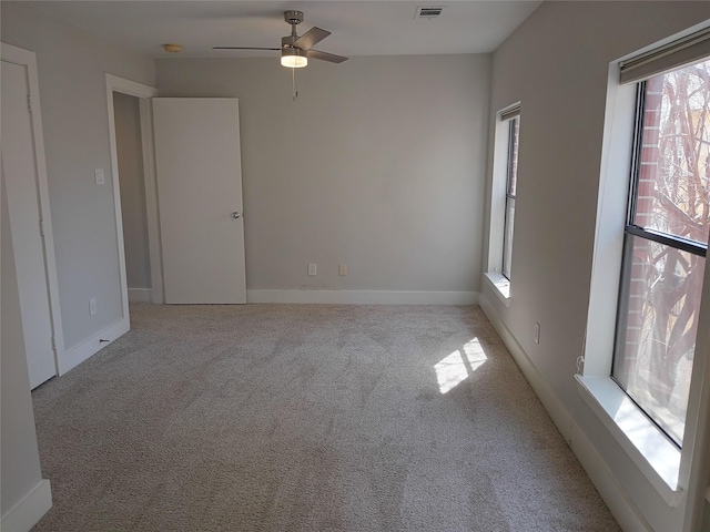 carpeted spare room featuring ceiling fan and baseboards