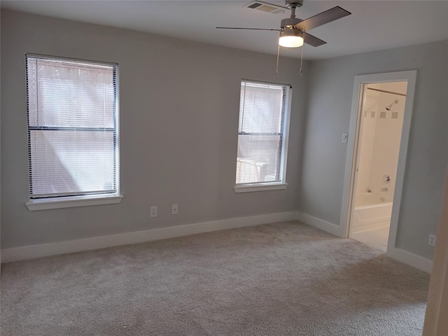 carpeted empty room with a ceiling fan, visible vents, and baseboards