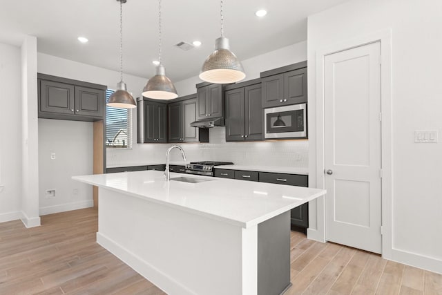 kitchen with under cabinet range hood, light wood-style floors, light countertops, backsplash, and built in microwave