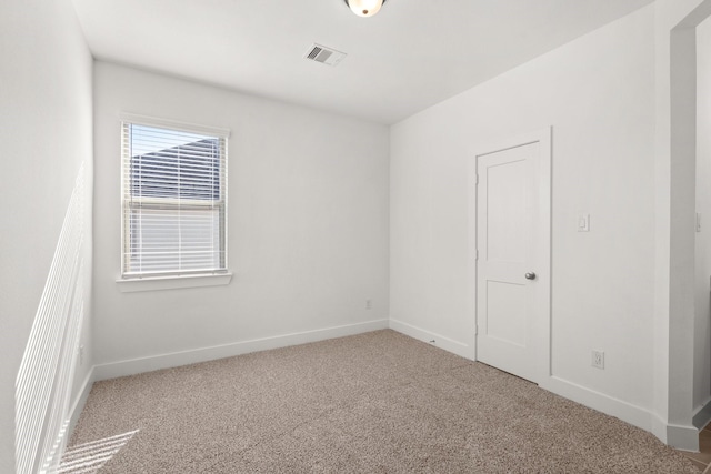 carpeted empty room with visible vents and baseboards