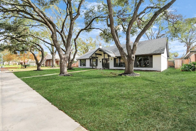 view of front of property featuring a front lawn and roof with shingles