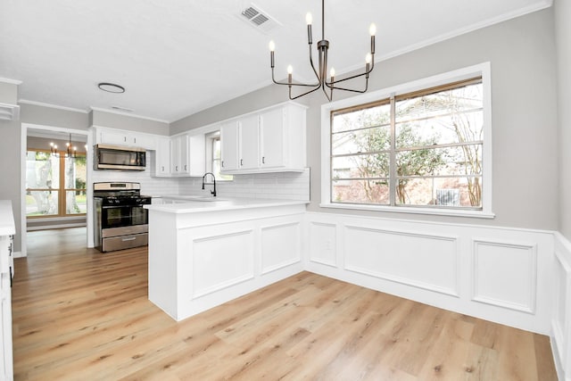 kitchen with white cabinets, appliances with stainless steel finishes, a notable chandelier, light countertops, and a sink