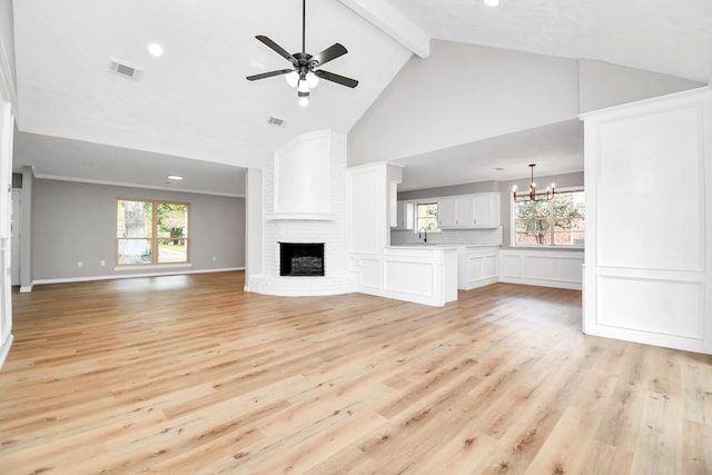 unfurnished living room featuring light wood-style flooring, ceiling fan with notable chandelier, a fireplace, visible vents, and beam ceiling