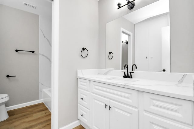 full bath with visible vents, toilet, vanity, wood finished floors, and baseboards