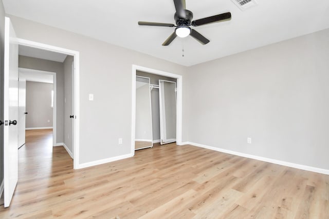 unfurnished bedroom featuring a ceiling fan, baseboards, visible vents, light wood-style floors, and a closet