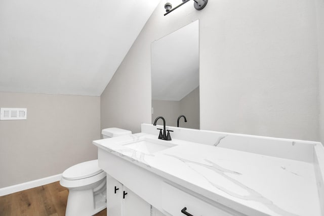 bathroom with visible vents, toilet, vaulted ceiling, vanity, and wood finished floors