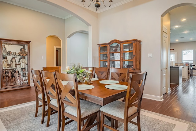 dining space featuring dark wood-style floors, arched walkways, crown molding, recessed lighting, and baseboards