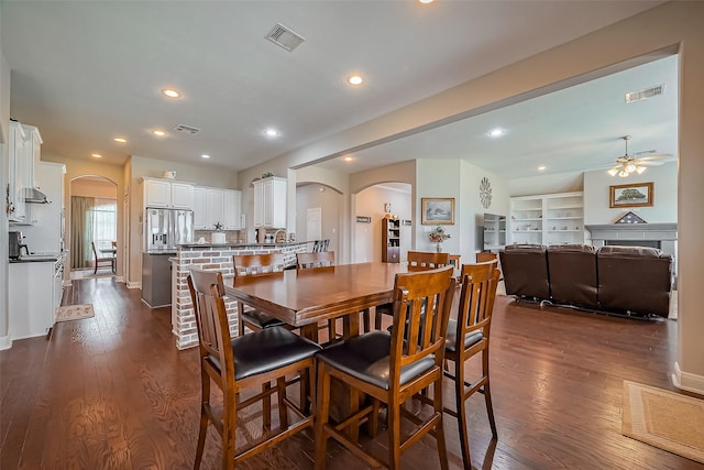 dining space with arched walkways, dark wood-style floors, and visible vents