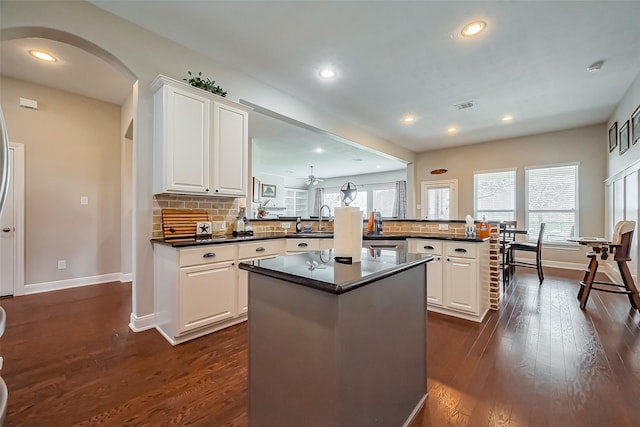 kitchen with dark wood-type flooring, dark countertops, visible vents, and a peninsula